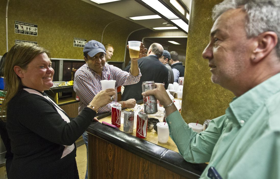 Nan Buziak Lexow, left, Srikanth Reddy, center, and Mark DeMonte, right, raise a toast while riding the bar car on the 7:07 p.m. train from Grand Central Terminal